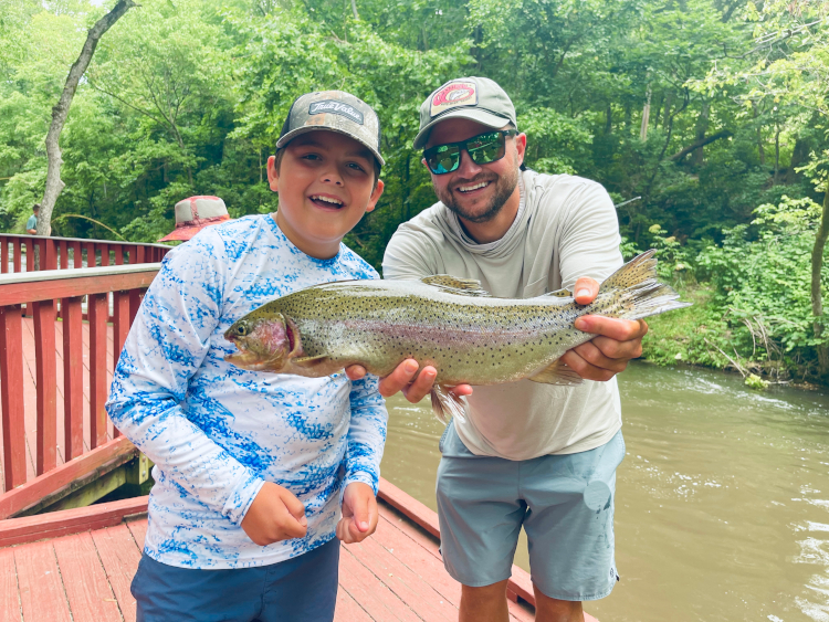 White River Fly fishing guide holding a beautiful Rainbow Trout with an excited young angler at Dry Run Creek.