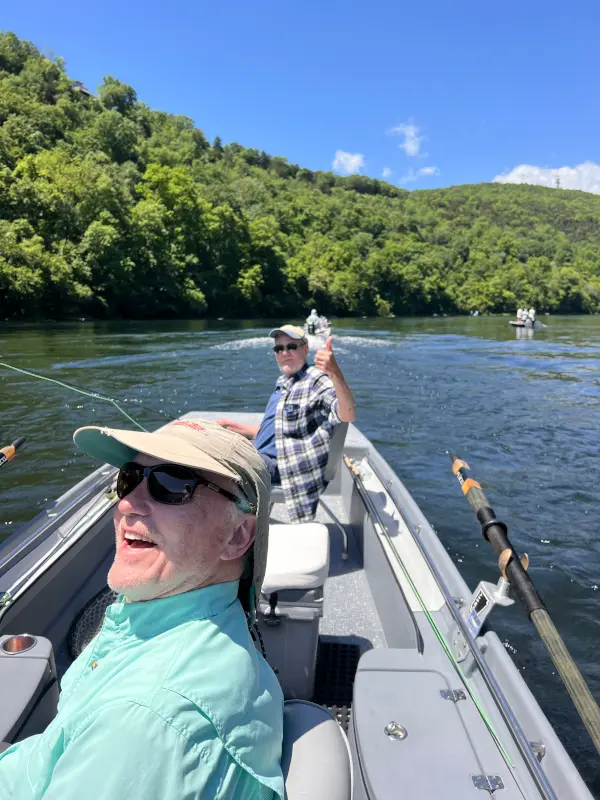Two White River fly fisherman giving a thumbs up in a trout boat as it makes its way back upriver to catch more Brown Trout.